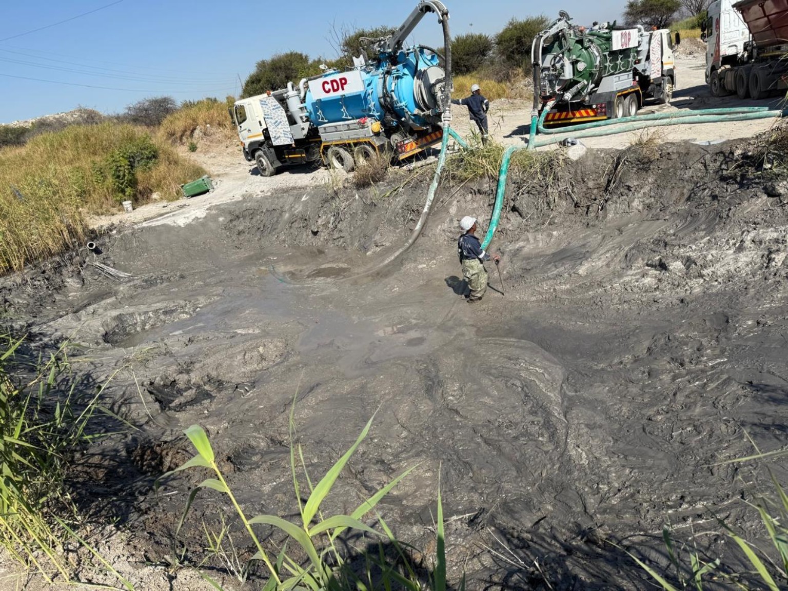 Workers using hoses for slurry removal with CDP vacuum tankers
