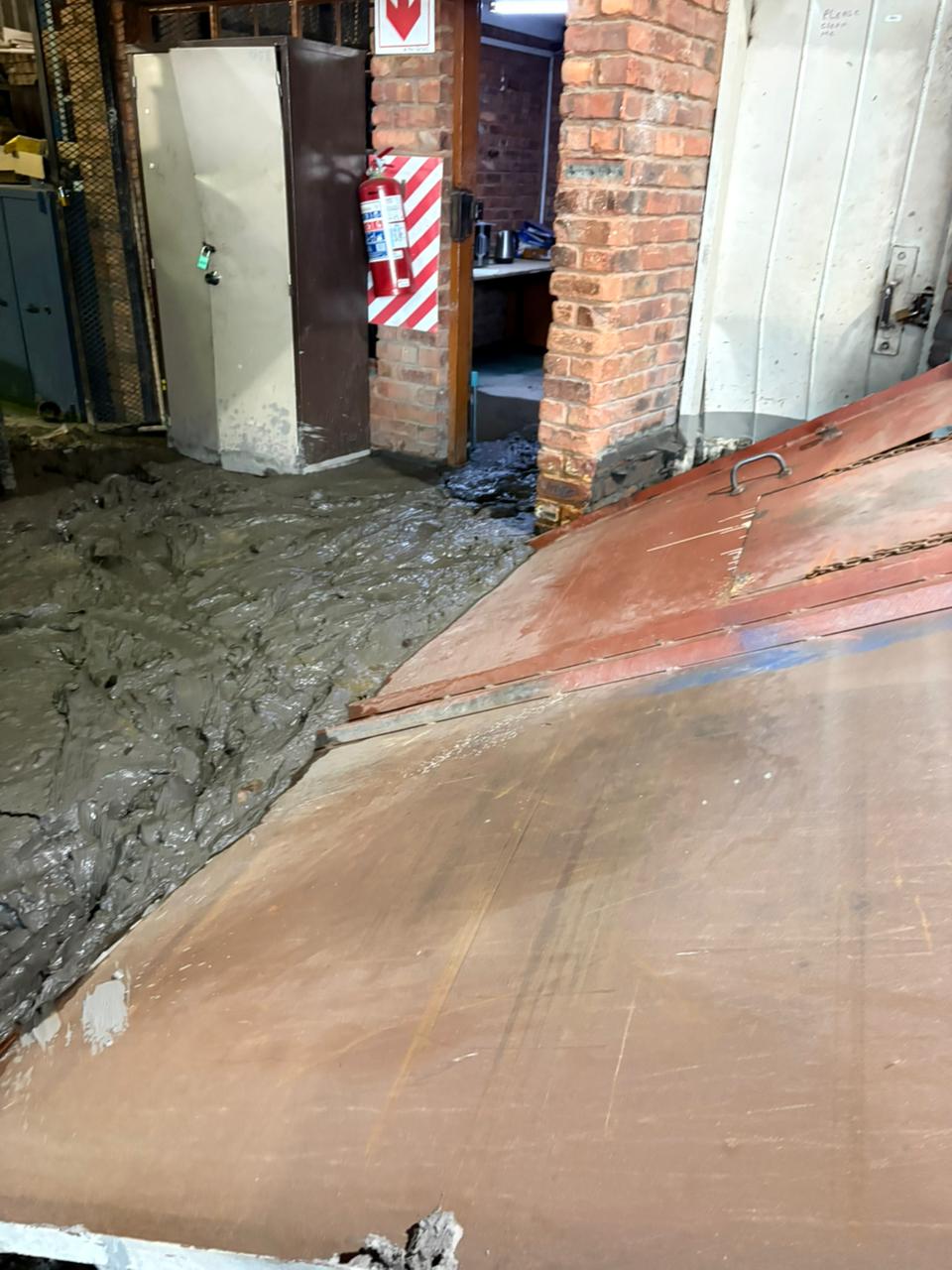 Sludge on the floor around a brick doorway and metal equipment